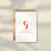 The Chilli Greeting Card from Good Juju Homeware features white premium card stock with orange branding and contact details, displayed on a brown envelope against a softly shadowed light surface.