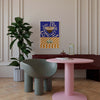 Modern interior with a pink table, green chair, and abstract art on the wall.