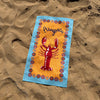 Colorful towel with a lobster design on sand