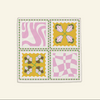 The Poppy Tile Florence Napkin by Good Juju Homeware is a square quilted piece featuring four vibrant panels with abstract floral and geometric patterns in pink, yellow, green, and white, adding an exquisite artistic touch to your tableware display.