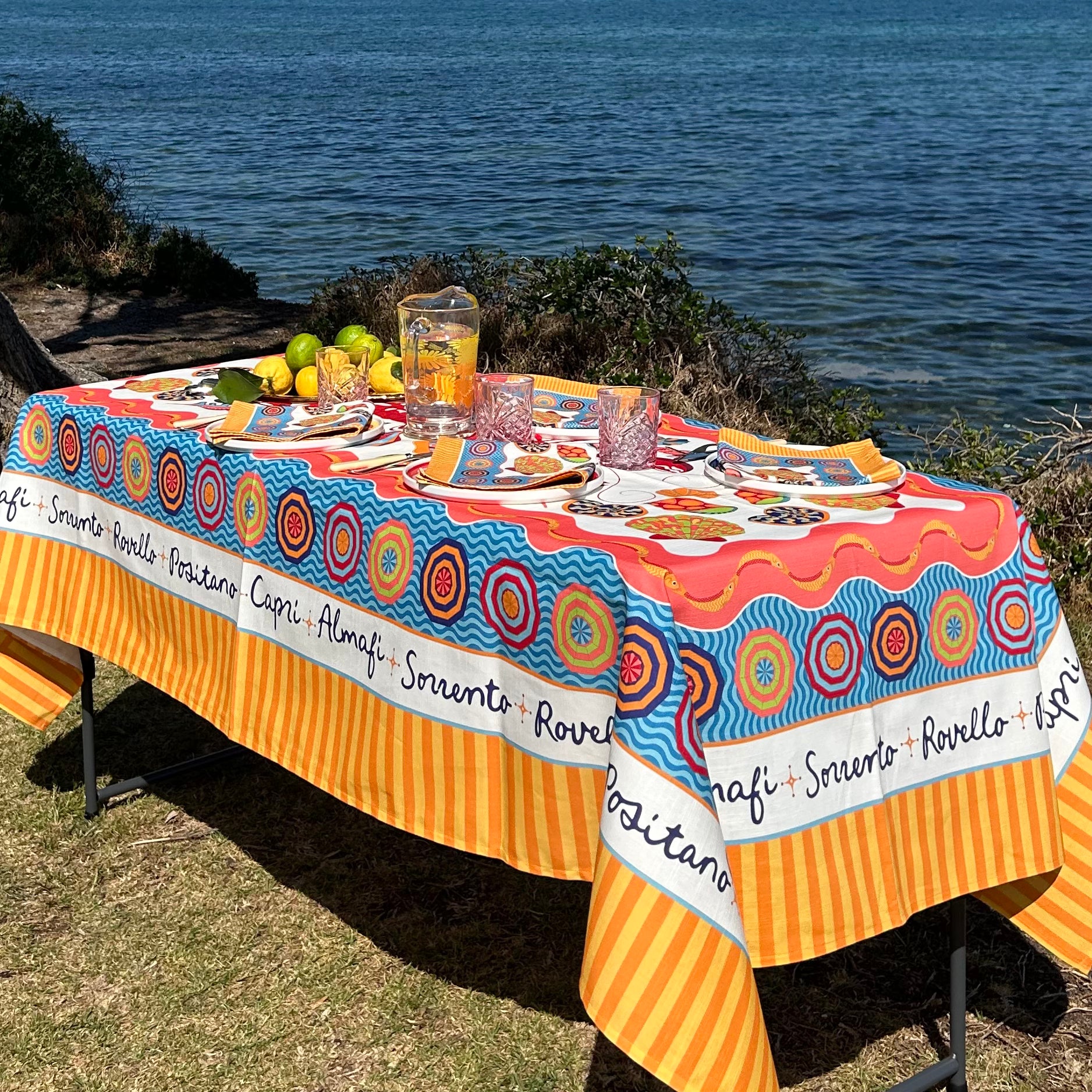 Colorful tablecloth with circular patterns and text on a table by the water