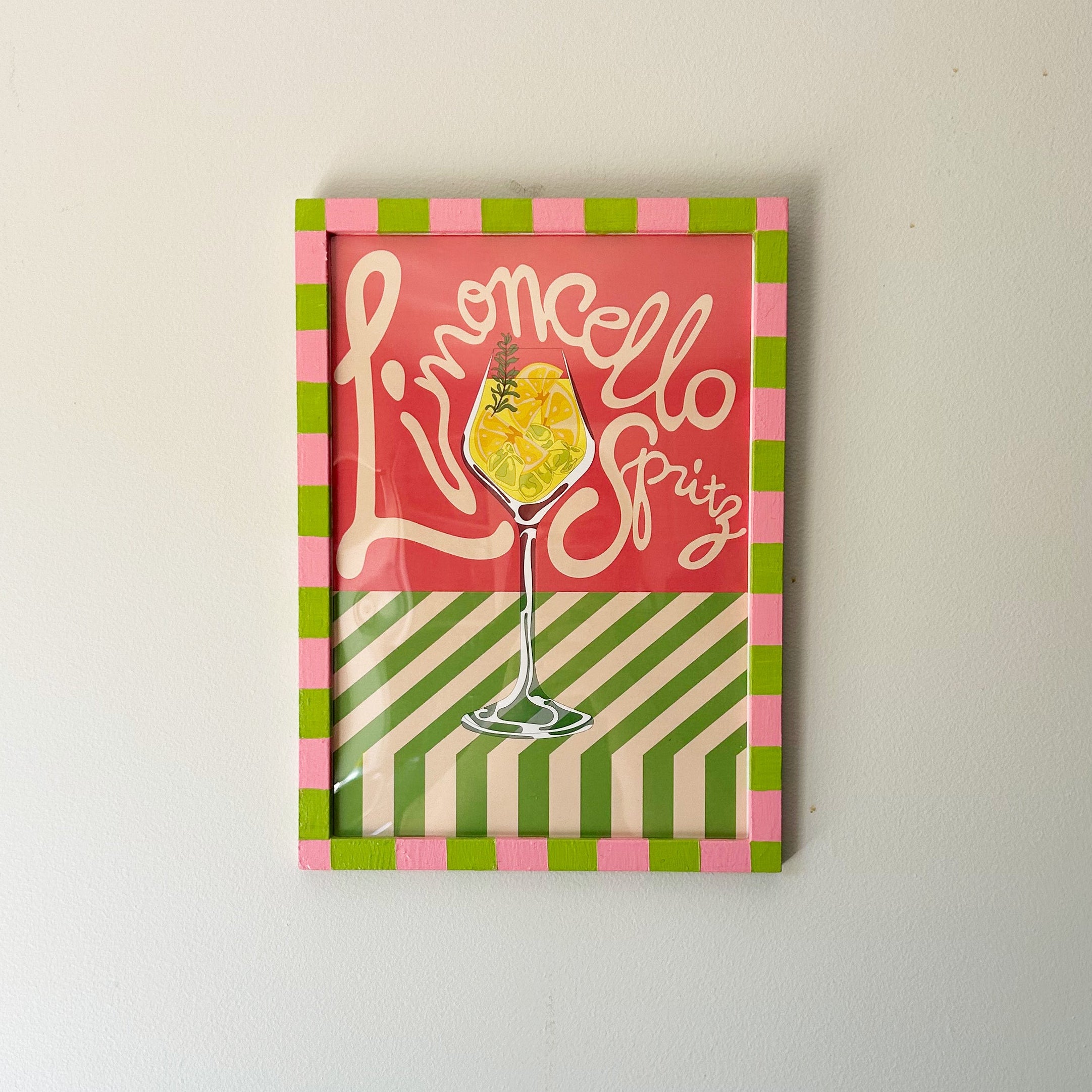Decorative sign with 'Limoncello Spritz' text and a glass illustration on a striped background.