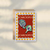 The Chilli Greeting Card by Good Juju Homeware features two chillies on a red background with a yellow checkered border and "PEPERONCINO" written twice. Printed on premium card stock, it brings Mediterranean charm to any occasion.