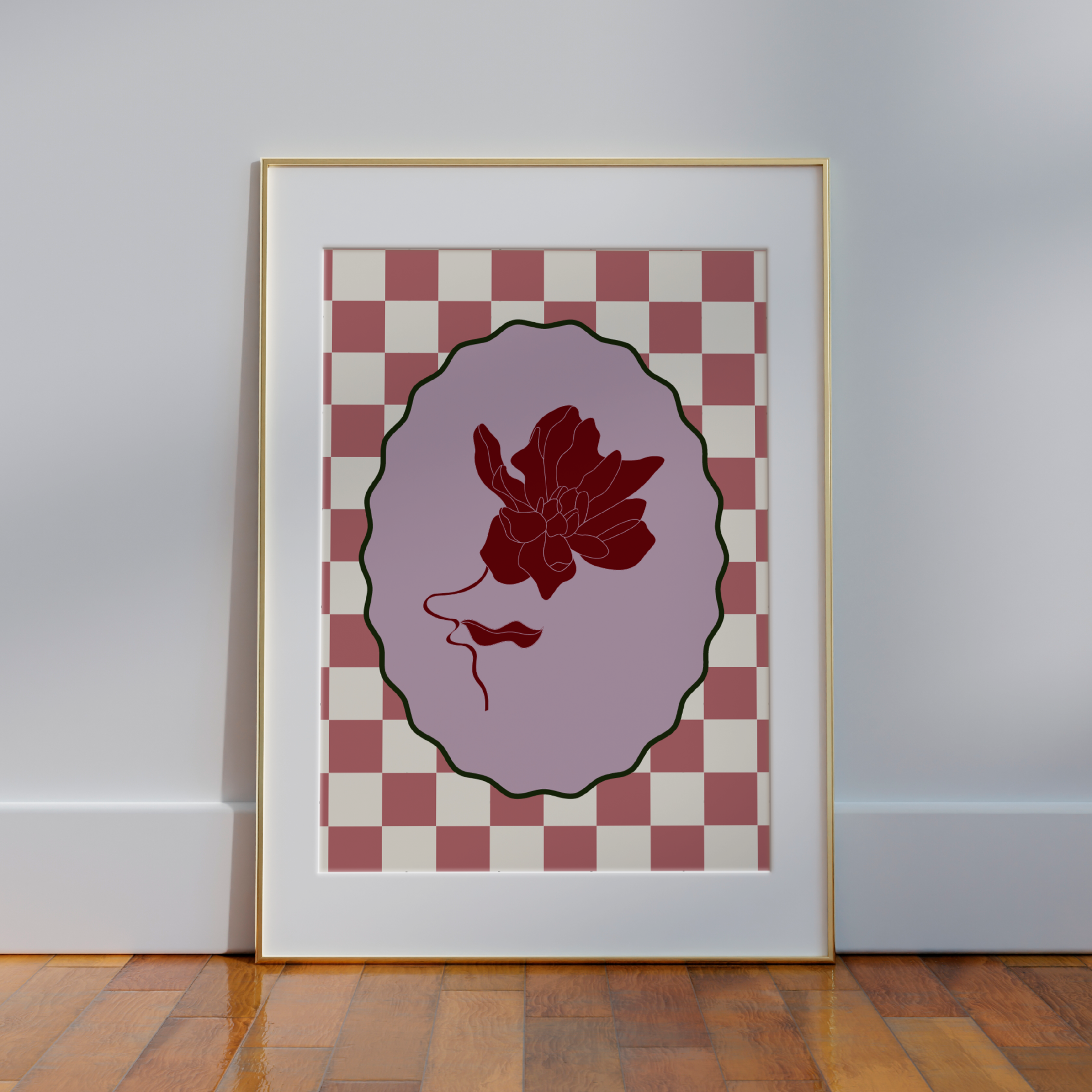 The Framed Magnolia Venice Wall Art by Good Juju Homeware showcases a floral silhouette within an oval on a checkered backdrop, resting against a wooden floor. It adds a funky yet sophisticated floral touch to any space, blending elegance with creative flair.