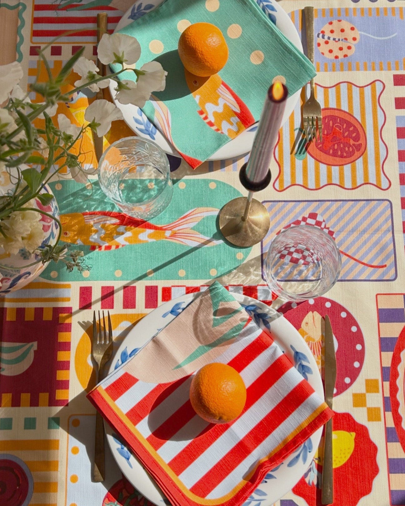 Colorful table setting with patterned placemats, cutlery, and decorative elements.
