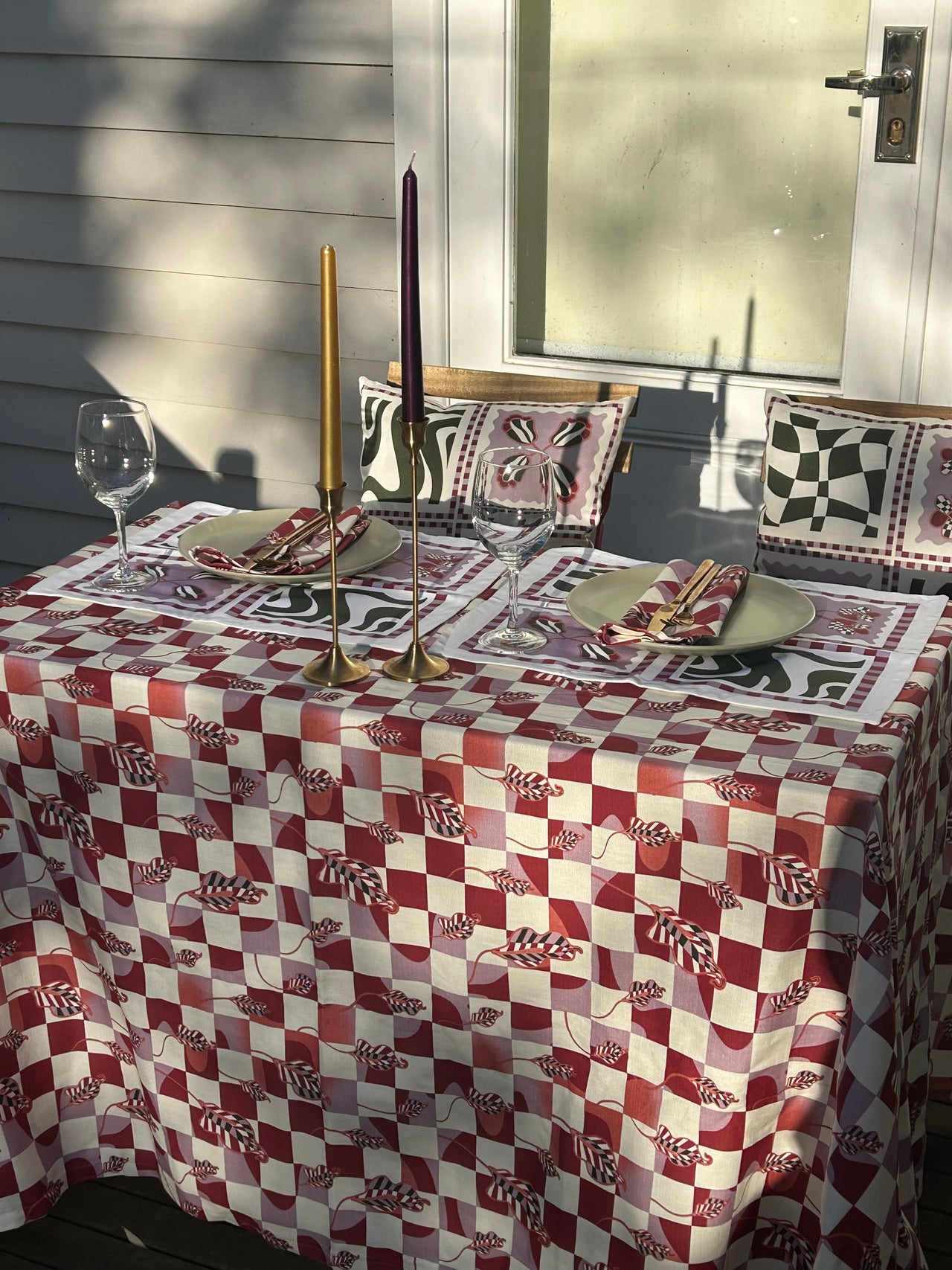 A Checkered Calla Lily tablecloth from Good Juju Homeware, featuring a red and white checkered design.