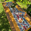 Colorful table runner with lobster design on a wooden table outdoors.