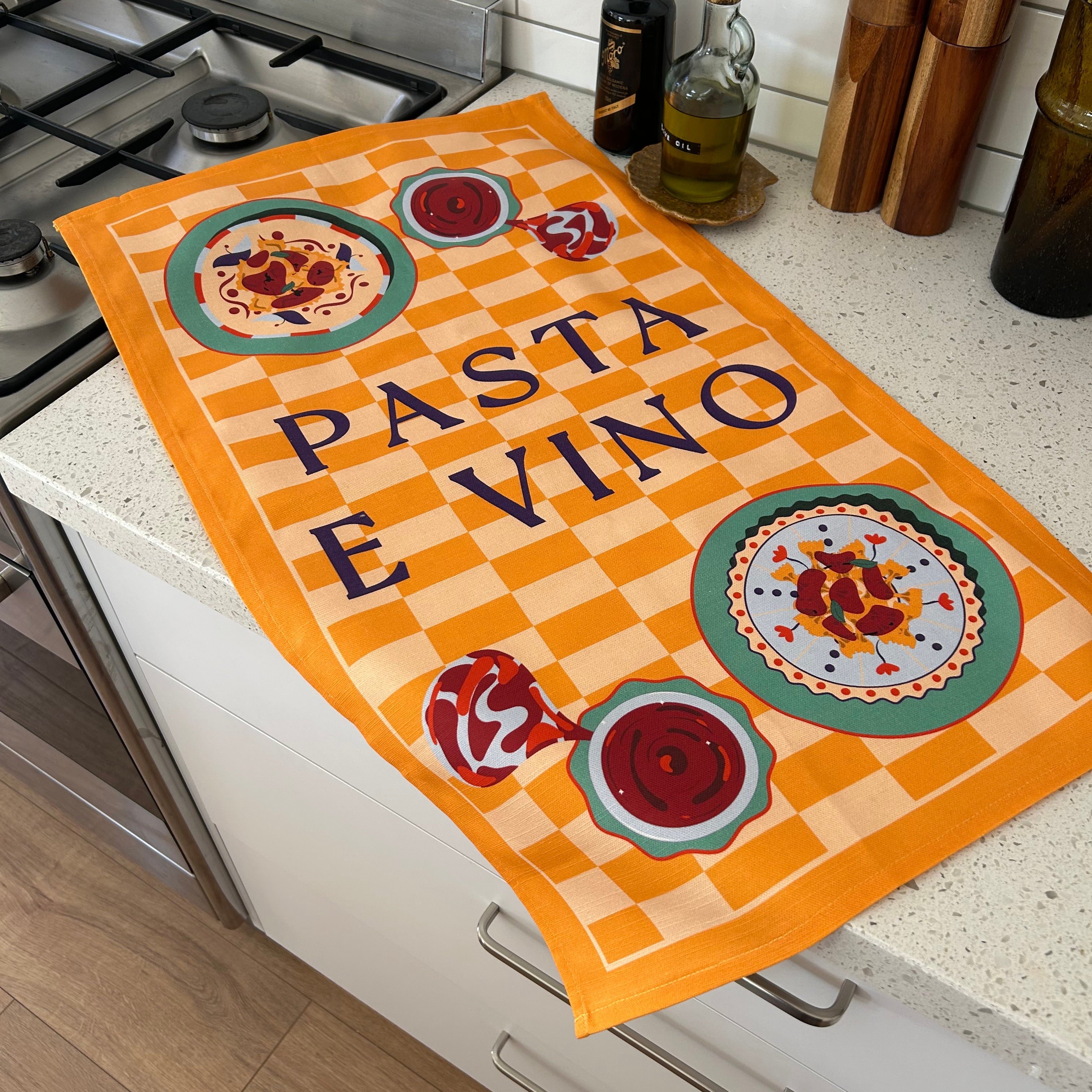 Decorative kitchen towel with 'Pasta e vino' text next to a stove