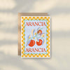 The Pasta E Vino Greeting Card by Good Juju Homeware features illustrated oranges and leaves with a yellow checkered border. "ARANCIA" is printed in red at the top and bottom on premium card stock for a quality finish.